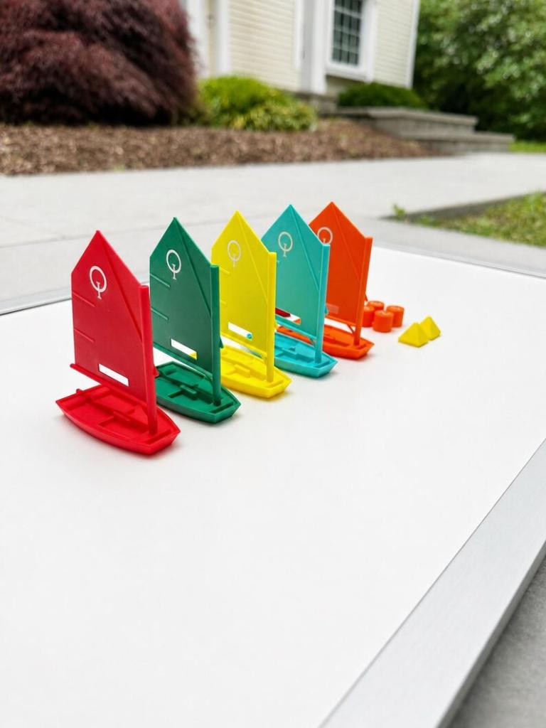 Five color-coded Opti sailboat tokens lined up